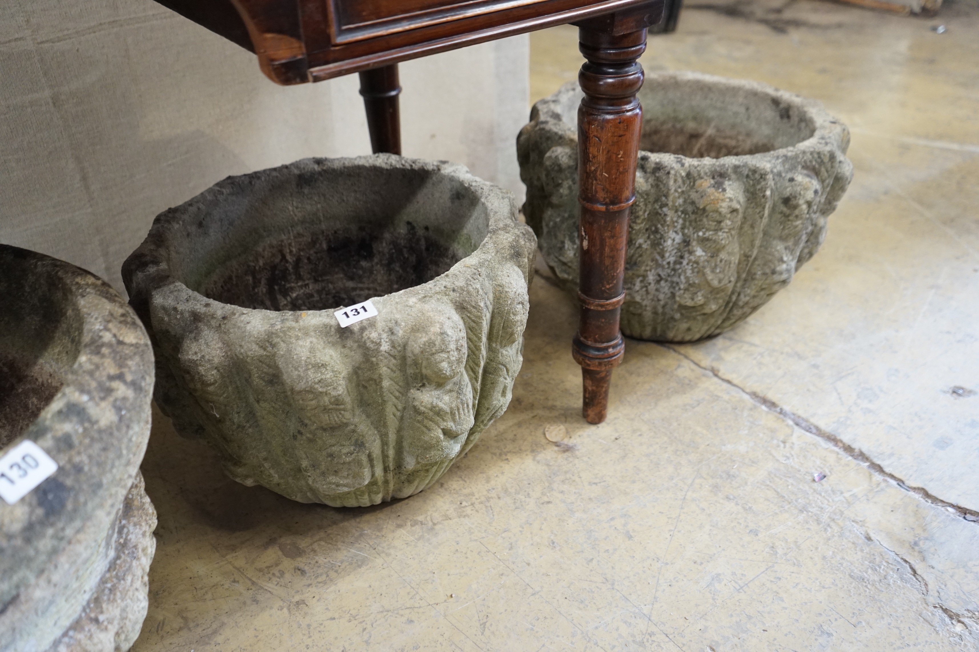 A pair of circular reconstituted stone '12 apostles' garden urns diameter 40cm height 28cm